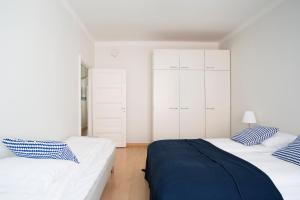 ヘルシンキにある2ndhomes Gorgeous 2BR apartment by the Esplanade Parkの白いキャビネットと青い枕が備わるベッドルームのベッド2台