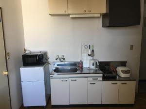 małą kuchnię ze zlewem i lodówką w obiekcie コンドミニアムホテル Stay inn Blue 301号室 w mieście Hukue