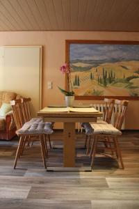 een eetkamer met een tafel en stoelen en een schilderij bij Ferienwohnung im Grünen in Diesbar-Seusslitz
