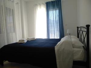 a bedroom with a bed with blue sheets and a window at Kymi Bay House in Platána