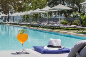 a drink and a hat on a table near a swimming pool at Rodostamo Hotel & Spa- Adults Friendly in Kommeno