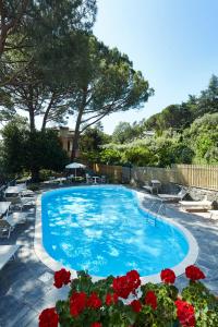 a large blue swimming pool with red flowers at Hotel Villa Adriana in Monterosso al Mare