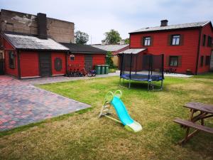 a playground with a slide and a swing set in a yard at Villa Victoria in Ventspils