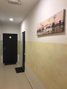 einen Flur mit einer schwarzen Tür und einem Gemälde an der Wand in der Unterkunft Helada Apartments in Tivat