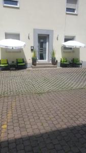 eine Terrasse mit Bänken und Sonnenschirmen vor einem Gebäude in der Unterkunft Holmbecks Hotel in Fürth