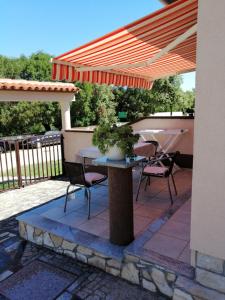 eine Terrasse mit einem Tisch und Stühlen unter einem Sonnenschirm in der Unterkunft Apartments Vitae in Pula