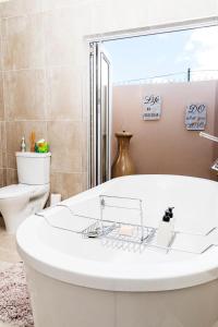 a white tub in a bathroom with a toilet at Settle Inn Self Catering Accommodation in Colchester