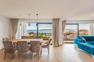 - une salle à manger avec une table, des chaises et un canapé bleu dans l'établissement Apartmani Arapovic, à Baška Voda