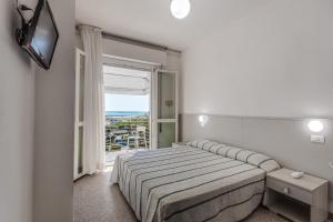 a white bedroom with a bed and a window at Hotel Blues in Cervia