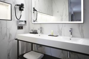 a white bathroom with a sink and a mirror at Riu Plaza España in Madrid