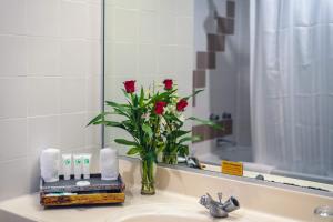 a bathroom sink with a vase with roses in it at Hotel Cambodiana in Phnom Penh