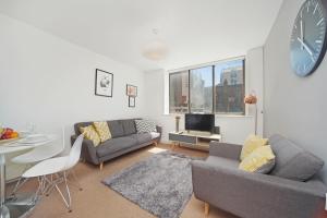 a living room with a couch and a table and a clock at 2 Bed Cosy Apartment in Central London Fitzrovia FREE WIFI by City Stay Aparts London in London
