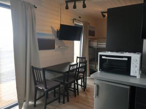 a kitchen with a table with chairs and a microwave at Black Beach Cottage Small in Ölfus