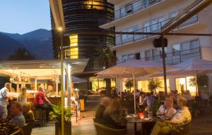 eine Gruppe von Personen, die außerhalb eines Gebäudes an Tischen sitzen in der Unterkunft Parkhotel Hall in Tirol in Hall in Tirol