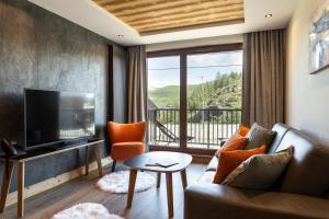 a living room with a couch and a television at Résidence Daria-I Nor by les Etincelles in L'Alpe-d'Huez