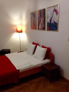1 dormitorio con 1 cama con sábanas blancas y almohadas rojas en Apartament Berko, en Cracovia