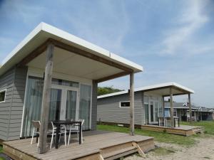 una casa con una mesa y sillas en una terraza en Beach Lodges Oostvoorne, en Oostvoorne