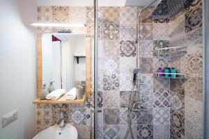 uma casa de banho com um chuveiro, um lavatório e um espelho. em A casa di Cassi em Modica