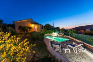 un patio trasero con piscina, sillas y una casa en Villa Istria, en Poreč