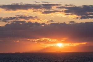 a sunset over the ocean with a mountain in the background at Four Seasons Astir Palace Hotel Athens in Athens