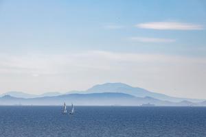 three sailboats in the water with mountains in the background at Four Seasons Astir Palace Hotel Athens in Athens