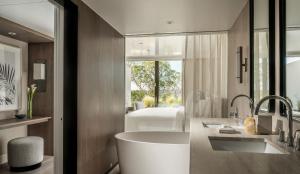 a bathroom with a tub and a bedroom with a bed at Four Seasons Astir Palace Hotel Athens in Athens