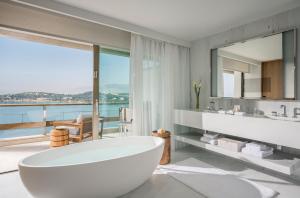 a bathroom with a large tub and a large window at Four Seasons Astir Palace Hotel Athens in Athens