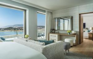 a bedroom with a living room with a large window at Four Seasons Astir Palace Hotel Athens in Athens