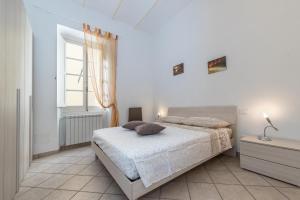 ein weißes Schlafzimmer mit einem Bett und einem Fenster in der Unterkunft Finalborgo - Casa Nanetti 6 posti in centro in Finale Ligure