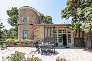 un bâtiment avec une table et des chaises devant lui dans l'établissement Les Gites du Chateau St Jacques d'Albas, à Laure-Minervois