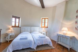 - une chambre avec 2 lits, 2 tables et 2 fenêtres dans l'établissement Les Gites du Chateau St Jacques d'Albas, à Laure-Minervois