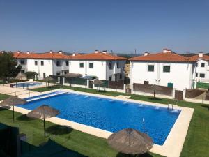 una piscina con sombrillas frente a algunos edificios en Casa Rural Valverde 6, en El Real de la Jara