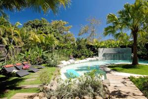 a swimming pool in a garden with chairs and trees at Villa Don Vito in Tamarindo