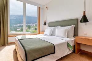 a bedroom with a large bed with a large window at Hotel da Fábrica in Manteigas +41 photos