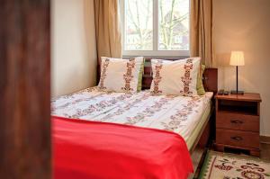 a bedroom with a bed with red sheets and a window at Chata Rybacka Saule in Ustka