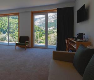 a living room with a couch and a desk with a computer at Hotel da Fábrica in Manteigas