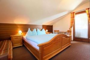 a bedroom with a large wooden bed with blue sheets at Haus Sonnheim in Kirchberg in Tirol