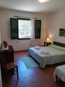 1 dormitorio con 2 camas, escritorio y ventana en Le Sughere, en Padru