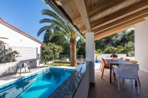 un patio con tavolo e sedie accanto alla piscina di Villa Artaturi a Mali Lošinj (Lussinpiccolo)