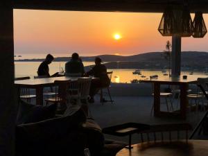 a group of people sitting at tables watching the sunset at Sunset View Hotel in Parikia