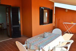 a table and chairs in a room with an orange wall at Villetta Amare Sardegna in Costa Rei