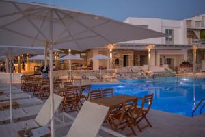 a pool with tables and chairs and an umbrella at Sunset View Hotel in Parikia