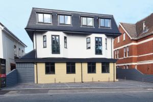 a yellow and white house with a black roof at Luxury 3 bedroom Apartment near Bournemouth Beach & Poole in Bournemouth