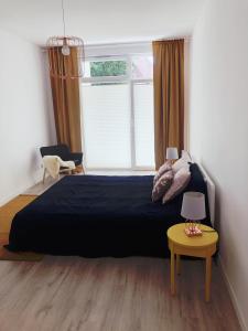 a bedroom with a black bed and a window at Apartament Kolorowy Przy Plazy in Giżycko