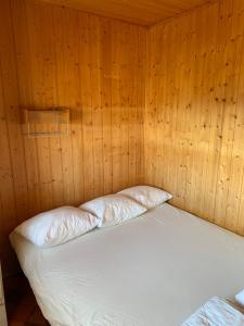 a bed in a wooden room with two pillows at Utsiktens turistgård in Järkvitsle