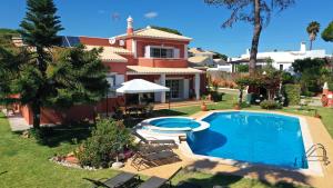 a villa with a swimming pool in front of a house at Vila Luz in Vilamoura