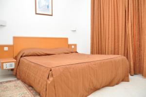 Dar El Manara Djerba Hotel & Aparts في حومة السوق: غرفة نوم بسرير كبير مع لحاف برتقالي