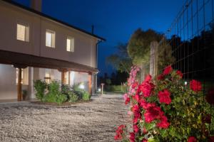 a fence with red flowers in front of a building at La Casa di Amedeo in Piombino Dese