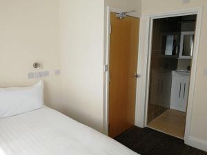 1 dormitorio con cama blanca y armario en Daisy Hotel, en Londres