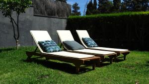 3 chaises longues avec des oreillers assis dans l'herbe dans l'établissement Margarida Charming House in Cascais, à Cascais